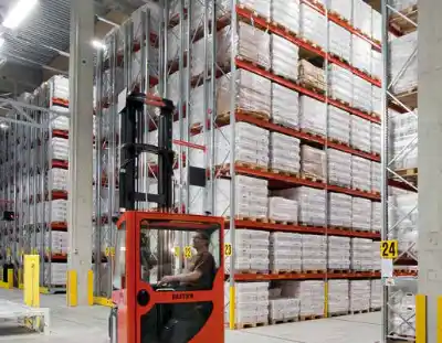 Pallet racking in a warehouse, with a reach truck working in the aisle